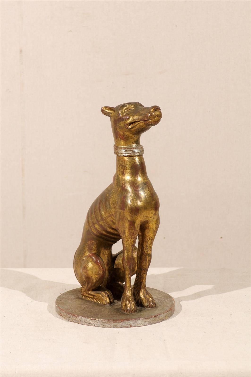 An Italian greyhound sculpture. This Italian greyhound or whippet dog nicely detailed depiction is made of wood with painted gold. The greyhound is sitting on a circular base. Mid-20th century.