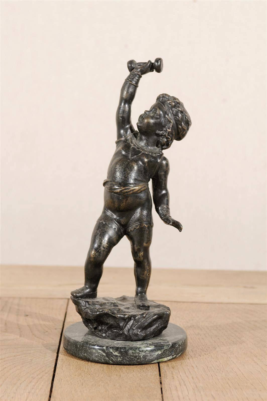 An Italian small size bronze sculpture of a putto on marble base, reproduction of a Classical statue. Mid-20th century.