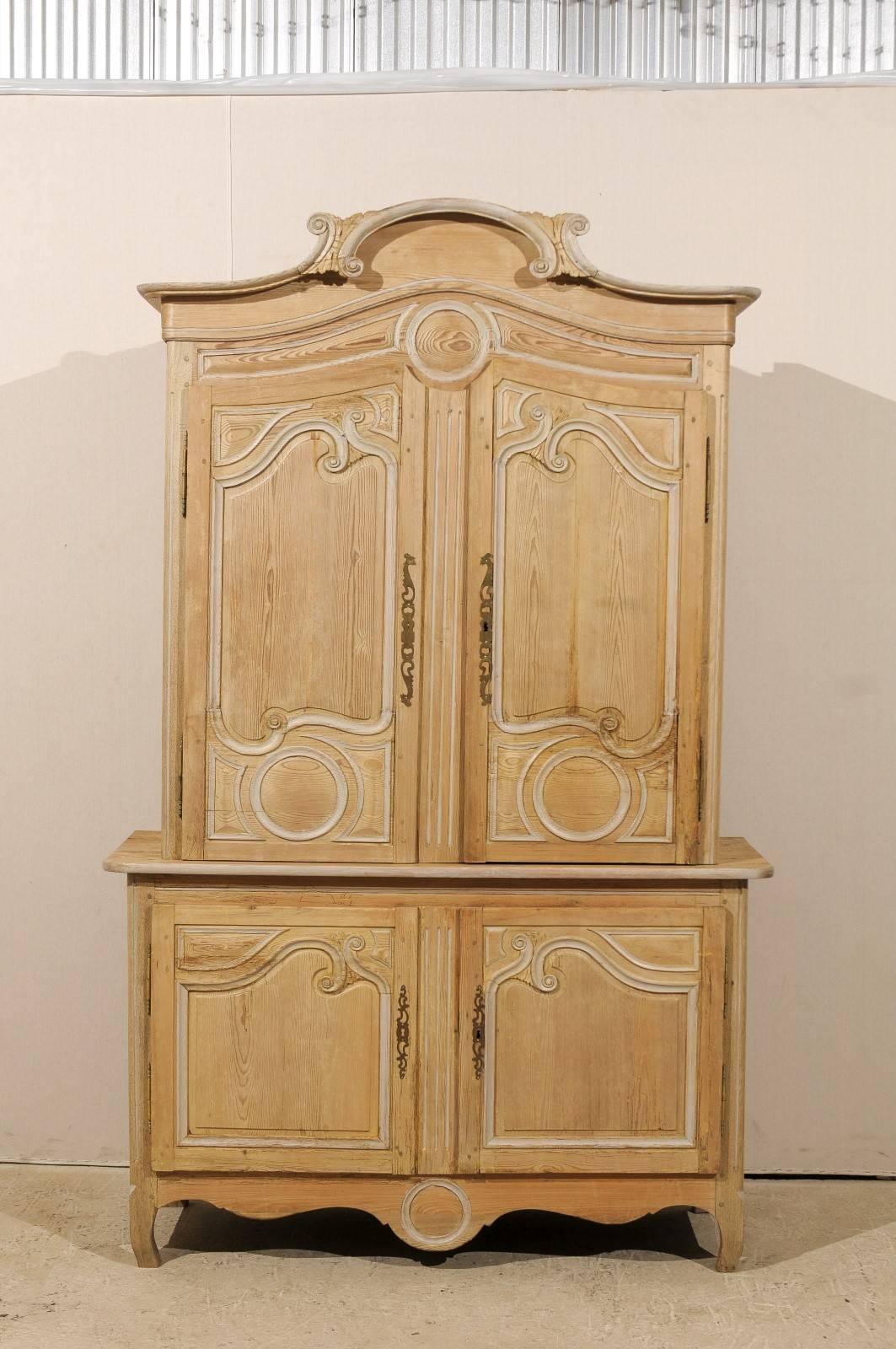 A French buffet à deux corps. This 19th century tall French cabinet has two doors over two lower doors. The pediment draws your attention up to the center with its C-scroll motif. The doors repeat the scrolling work. The section below the crest is