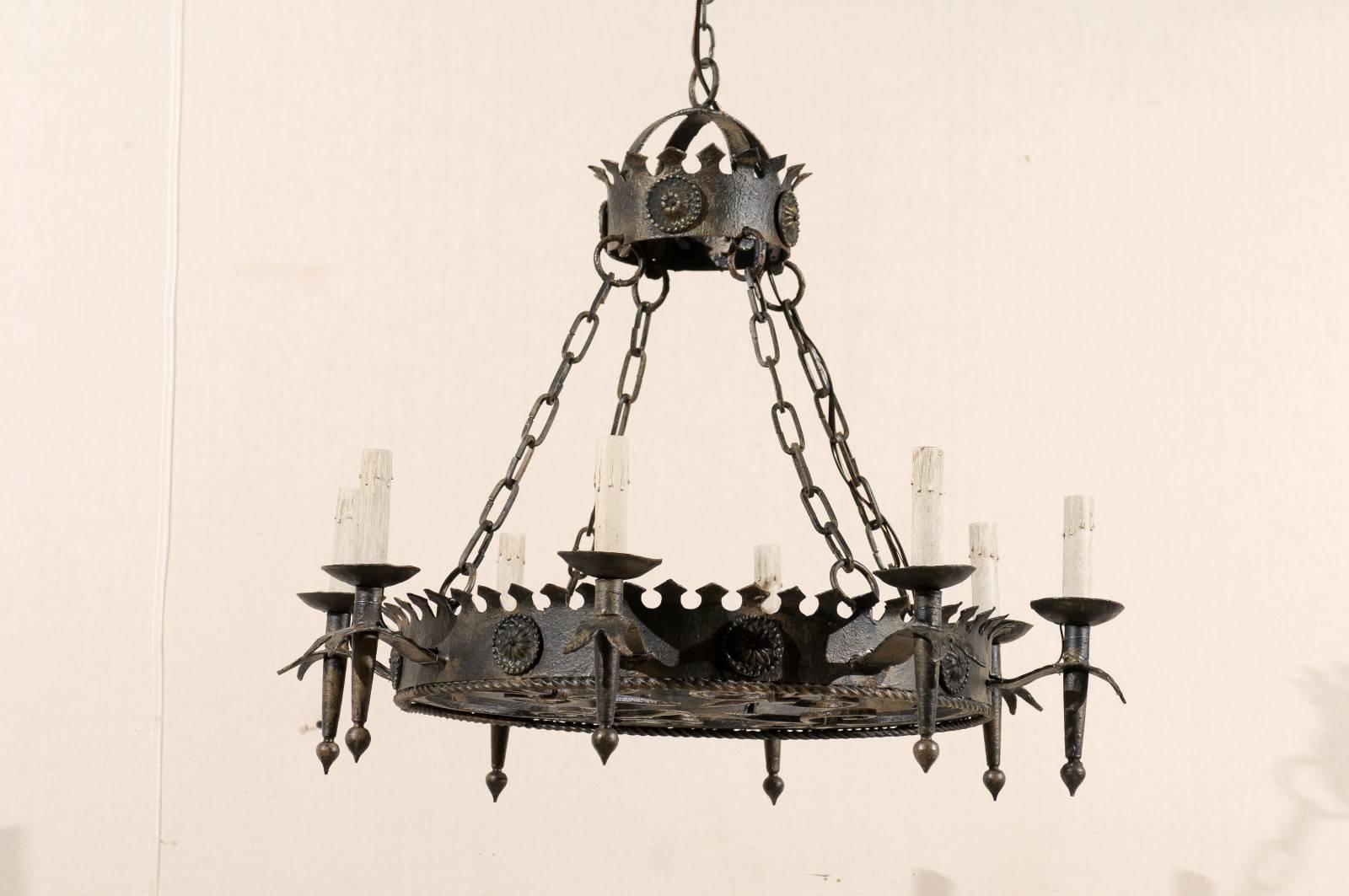 An elegant circular French vintage eight-light iron chandelier. This French chandelier from the mid-20th century features a circular ring that connects to a matching domed canopy by four chains. The torch shaped arms surround the larger, lower