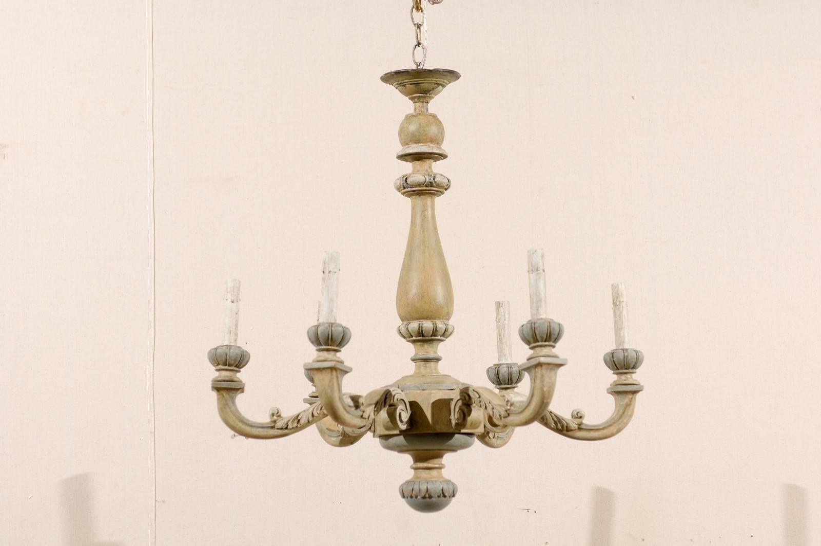 A French carved and painted wood six-light vintage chandelier. This French chandelier from the mid-20th century features a carved central column with six scrolled arms emerging outward that are each adorned with acanthus leaf motifs. This piece is