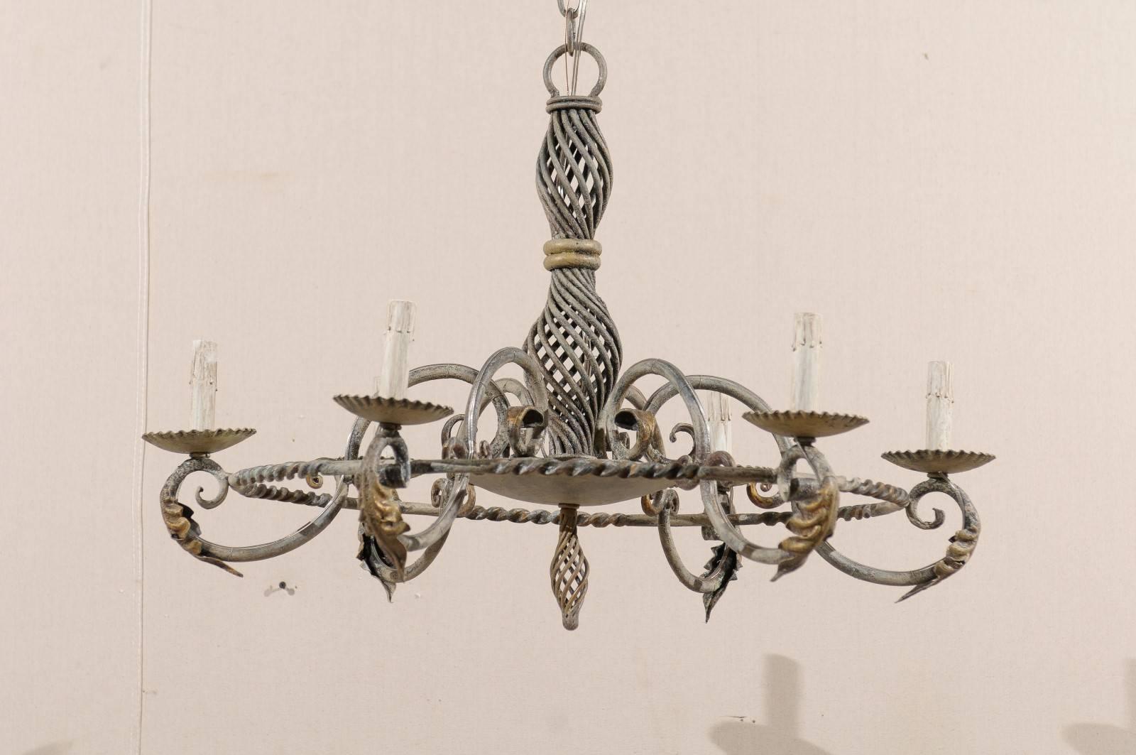 A French six-light painted iron vintage chandelier. This French iron chandelier from the mid-20th century features an intricately twisted central column with s-scrolled arms that attach to a circular ring midway to the lights. The arms are adorned