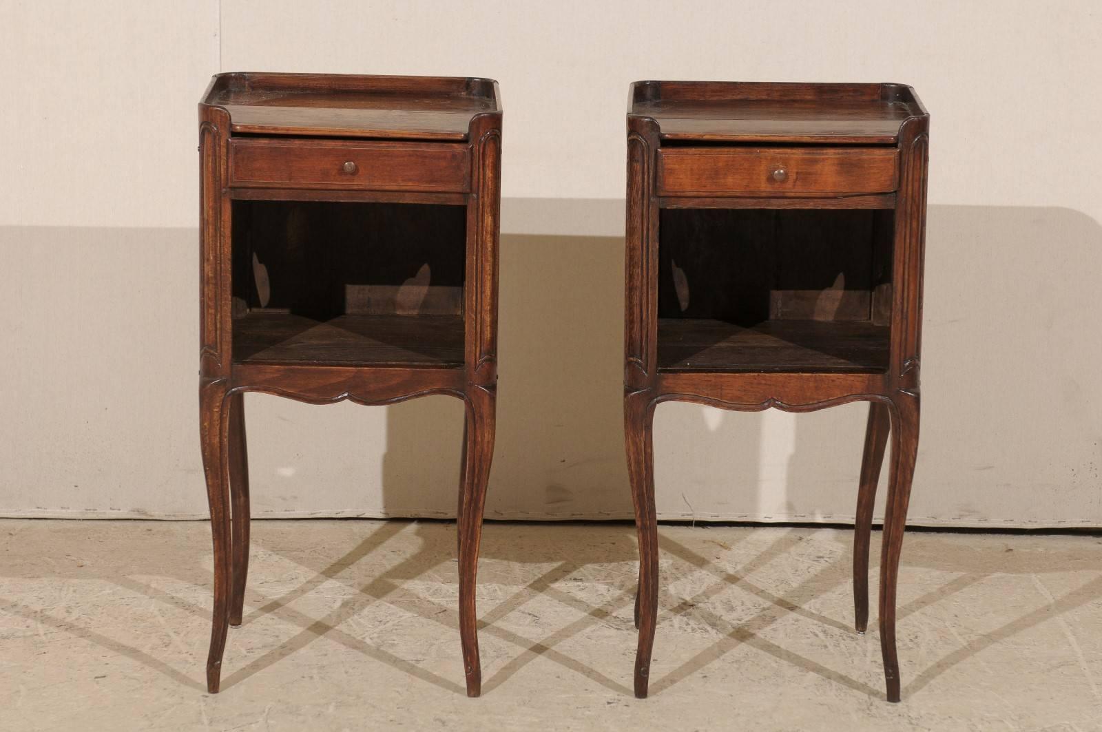 A pair of French 19th century side tables or nightstands. This pair of French stained wood bedside or side tables features a top drawer over an open lower shelf. The finish on the body is close to a Cabernet mahogany in color. The tabletop has