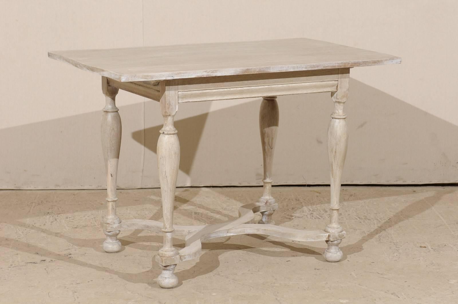 A Swedish 19th century Baroque style side table. This Swedish table has been custom painted in a light wash. This piece is adorned with nice, simple features, including a center cross stretcher, turned legs and ball feet. This medium size table