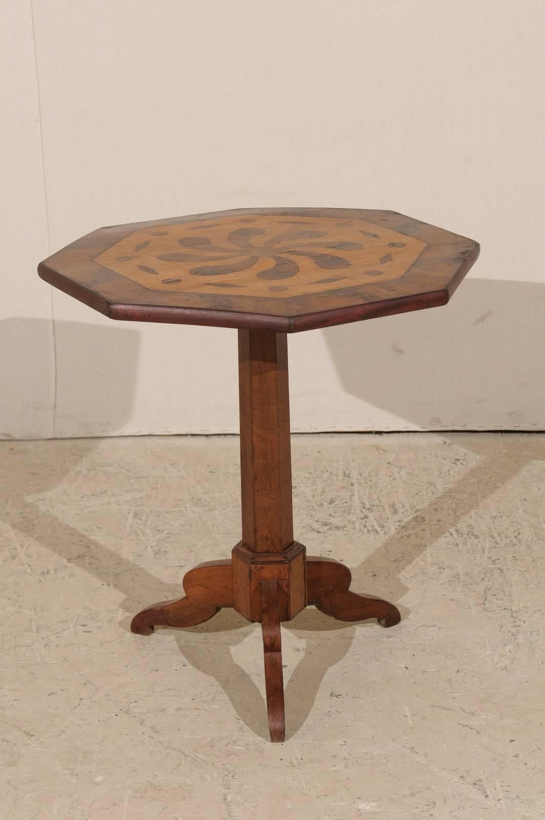 An Italian 19th century octagon occasional table. This Italian wood stained occasional table or side table features an octagon top which rests on a central pedestal column and tripod feet. The top is an inlaid wood design which mimics the octagon