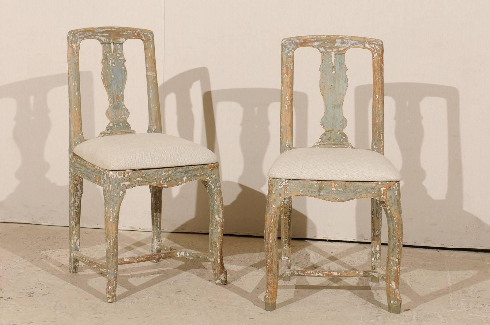 A pair of Swedish mid-18th century period Rococo side chairs. This pair of Swedish chairs features original paint, pierce splats and a cross stretcher at the bottom. The seats have been newly upholstered in a nice, neutral Belgian linen. These side