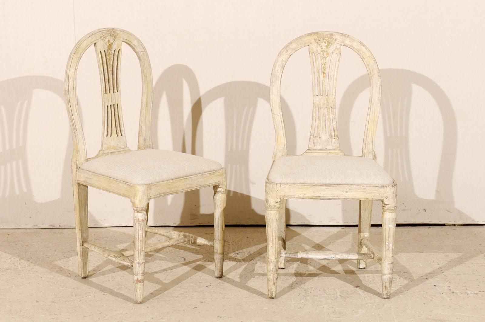 A pair of Swedish Provincial Gustavian wheat back side chairs. These Swedish chairs from the early 19th century have been scraped to their original color and feature round backs with a nicely carved top rail, fluted legs and a cross stretcher. The