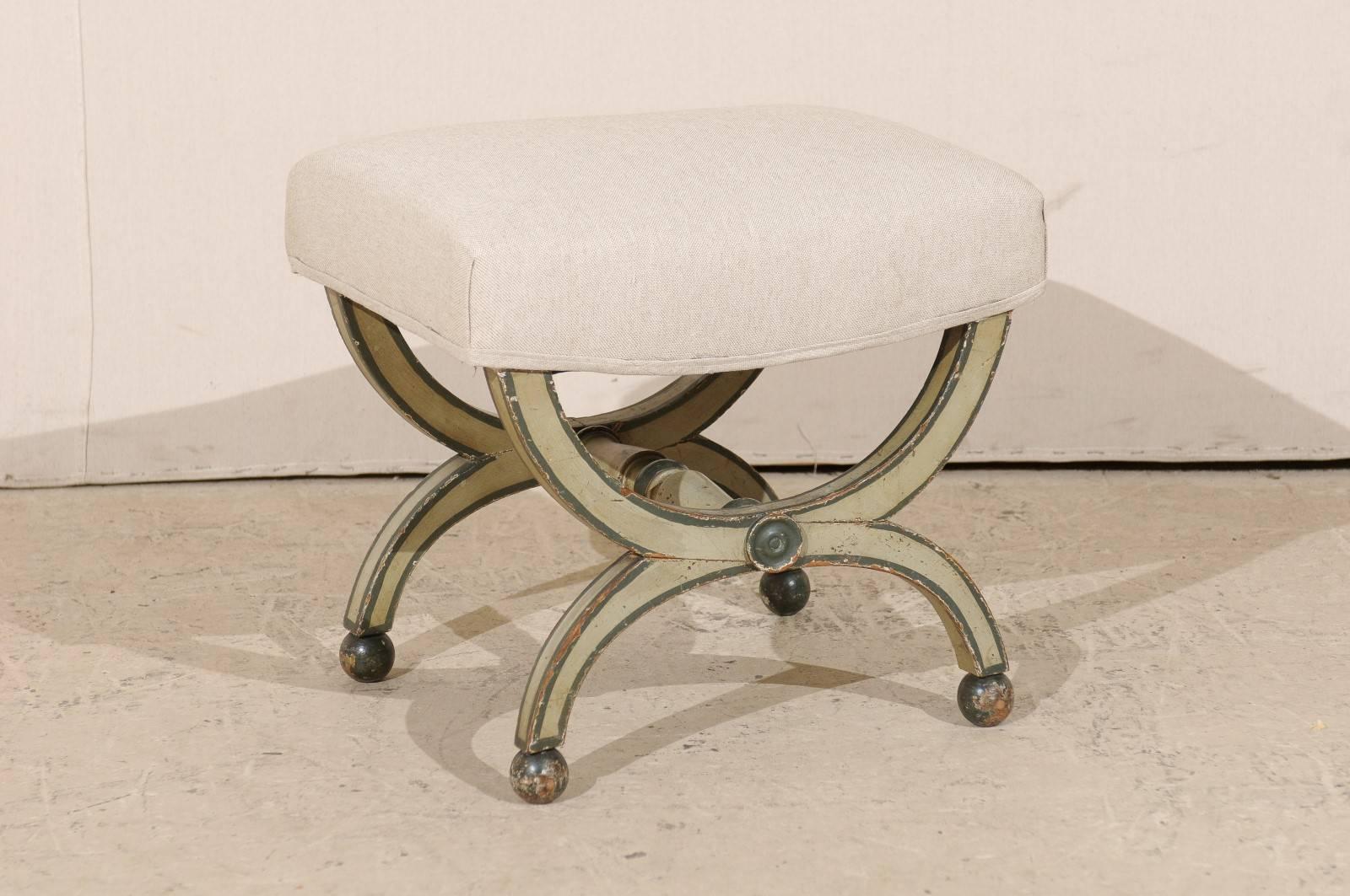 A French mid-19th century wood stool with original paint. This French Dante style stool features double half-moon legs that are connected by a turned cross stretcher. This stool sits on four ball feet and is adorned with circular rosette carvings on