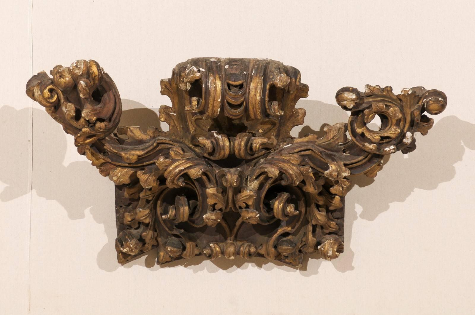 An Italian early 19th century giltwood fragment. This gilded wood Italian wall decoration features a Rococo style fragment made of various volutes. This piece also features richly carved acanthus leafs and other foliage motifs. This wall fragment
