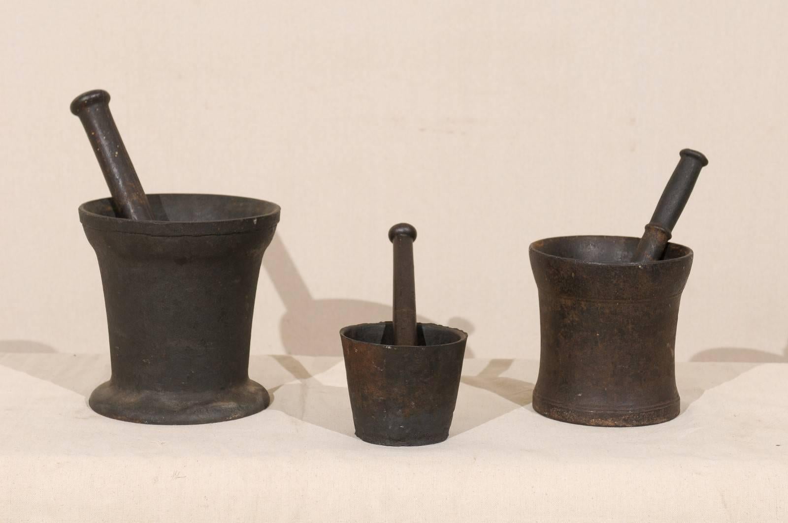 A set of three English mortars and pestles of various shapes and sizes. This set of vintage mortars and pestles was once used to grind various ingredients used for cooking. They are nicely weighted and make for a lovely decorative collection. This