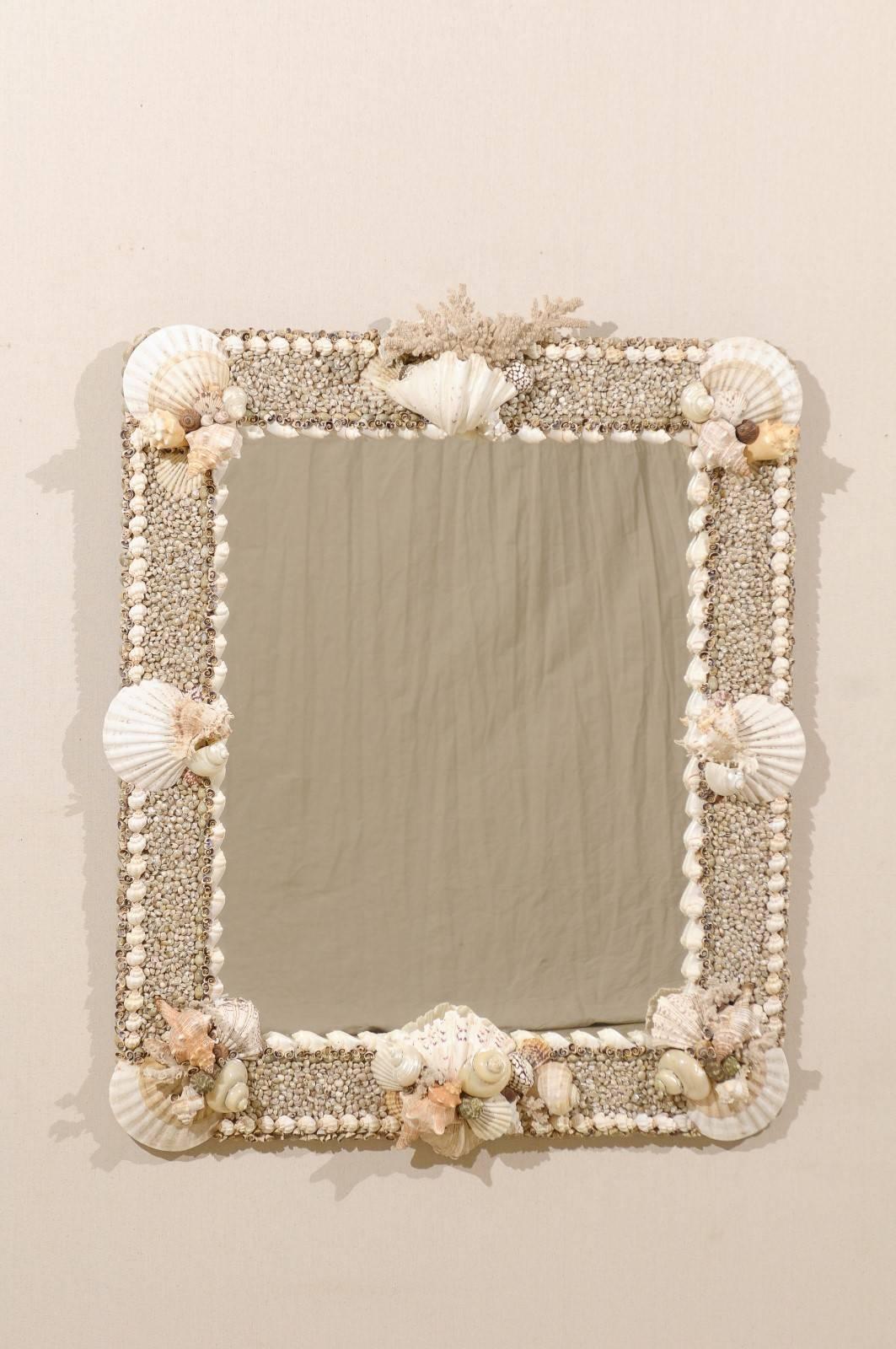 A shell and coral decorated wall mirror. This oceanic inspired mirror is comprised of various real shells, coral and ocean rock from the Indian Ocean and the Philippines. Bringing a taste of the outdoors in, this nautical mirror has a lovely seaside