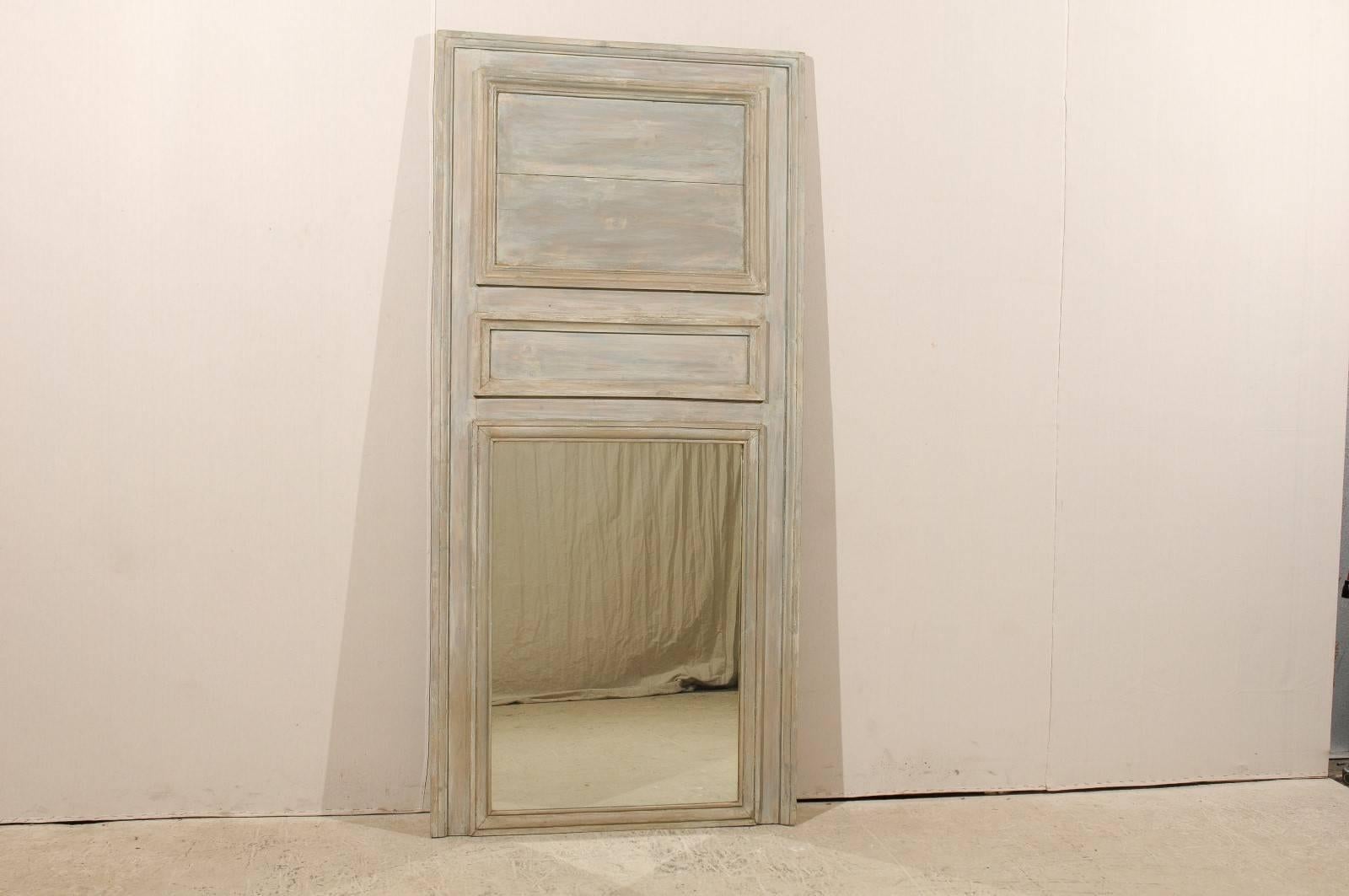 A French 19th century painted wood trumeau mirror. This mirror is adorned with two carved rectangular wooden panels of differing sizes at the top. It is painted in neutral soft taupe, grey and blue colors. This French mirror would add the perfect