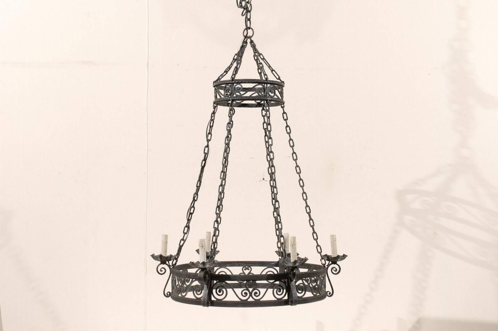 A French circular iron six-light chandelier. This elegant French chandelier from the mid-20th century features a central ring base with stylized scrolled motifs. There are six scrolled arms that lift off of the central ring and support the metal
