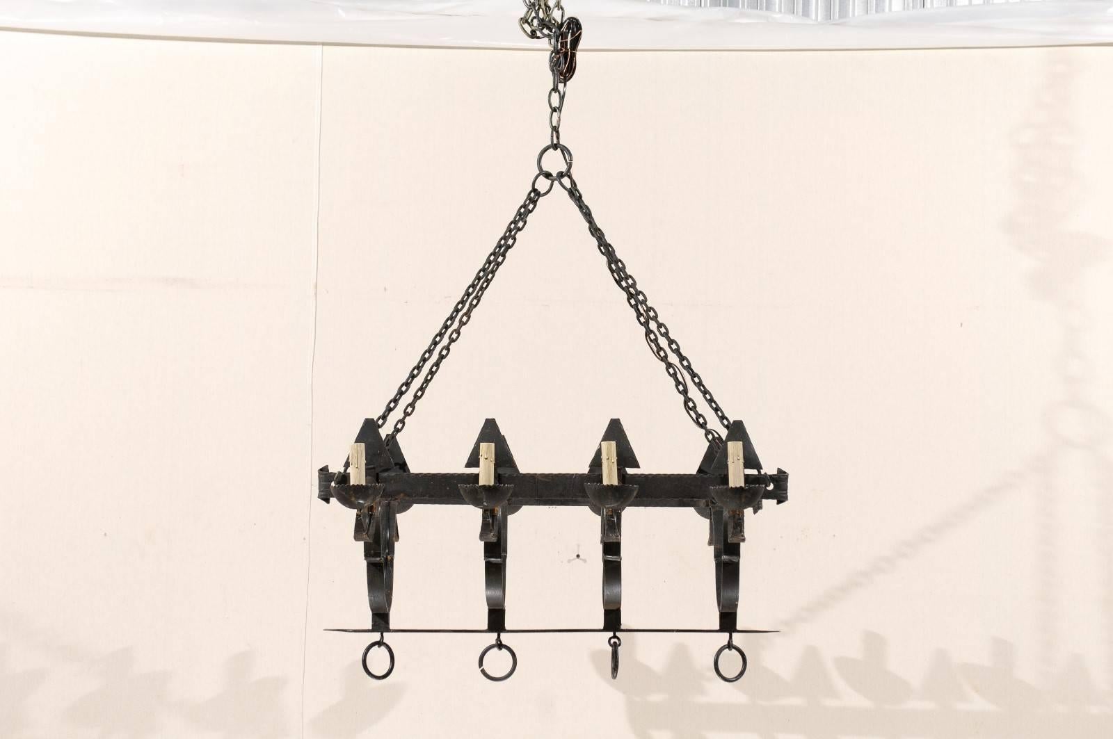 A French rectangular shaped forged iron eight-light chandelier. This French mid-20th century chandelier features two horizontal beams with scrolled ends, each of which support four upward pointing spears mounted along the two longer sides of the