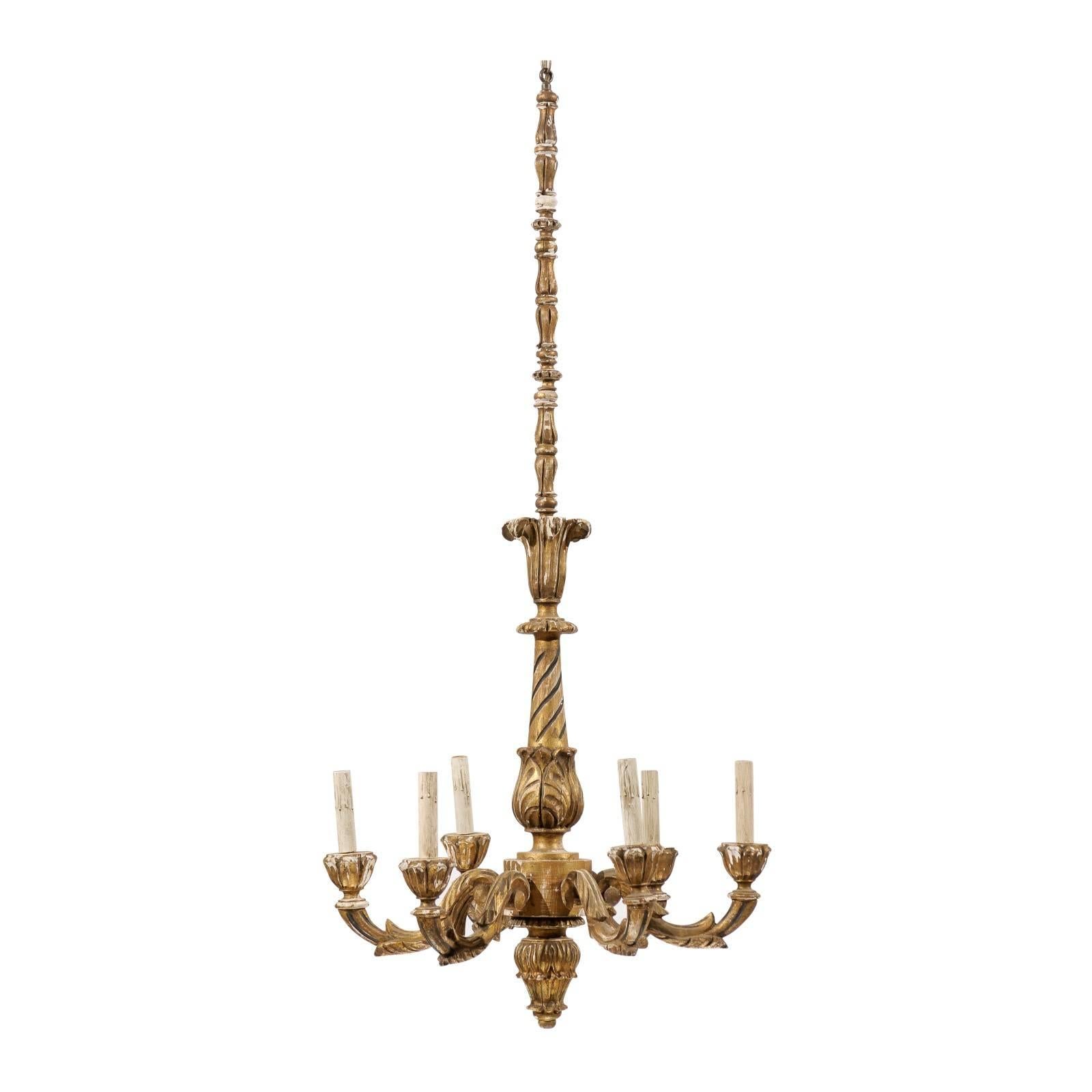A tall and slender French six-light giltwood chandelier with ornate decoration and beautiful aging. This piece is adorned with rich acanthus leaf carvings. The carvings are accented in a darker color in chosen spots to enhance the depth and overall