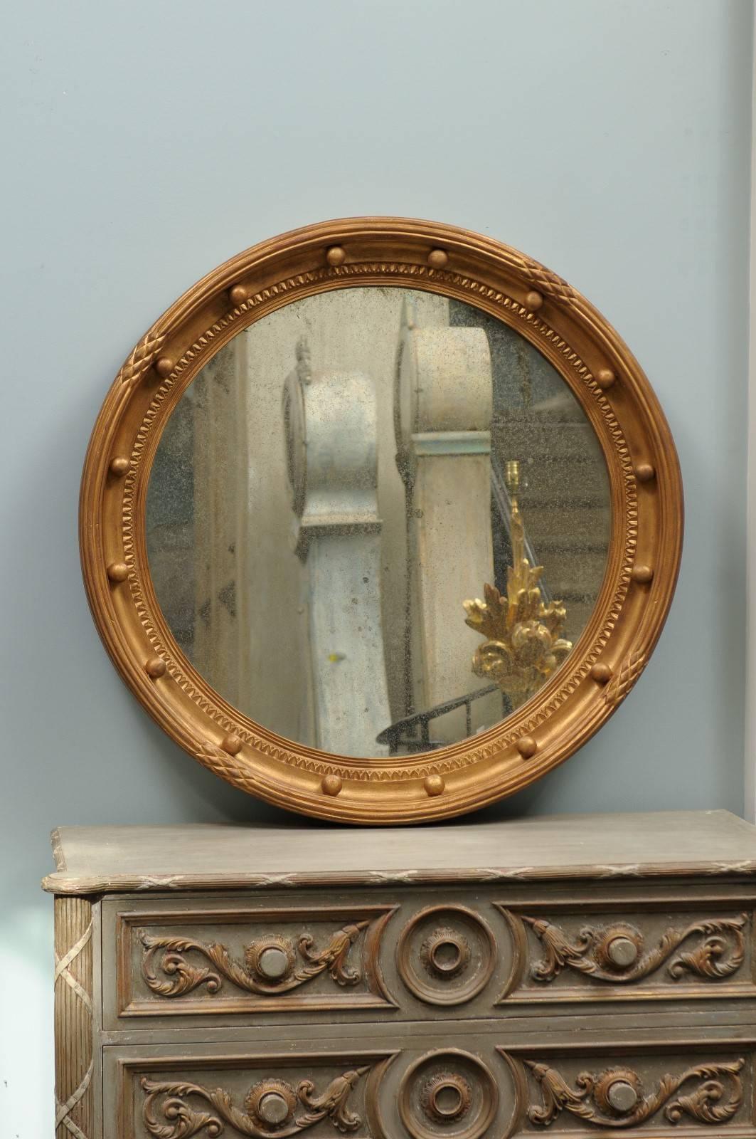 A gilded wood girandole bullseye round mirror. This girandole mirror features a gilded wood circular frame with small spheres, rhythmically spread out on the surround. The inside of the frame is decorated with an egg-and-dart reminiscent motif. The