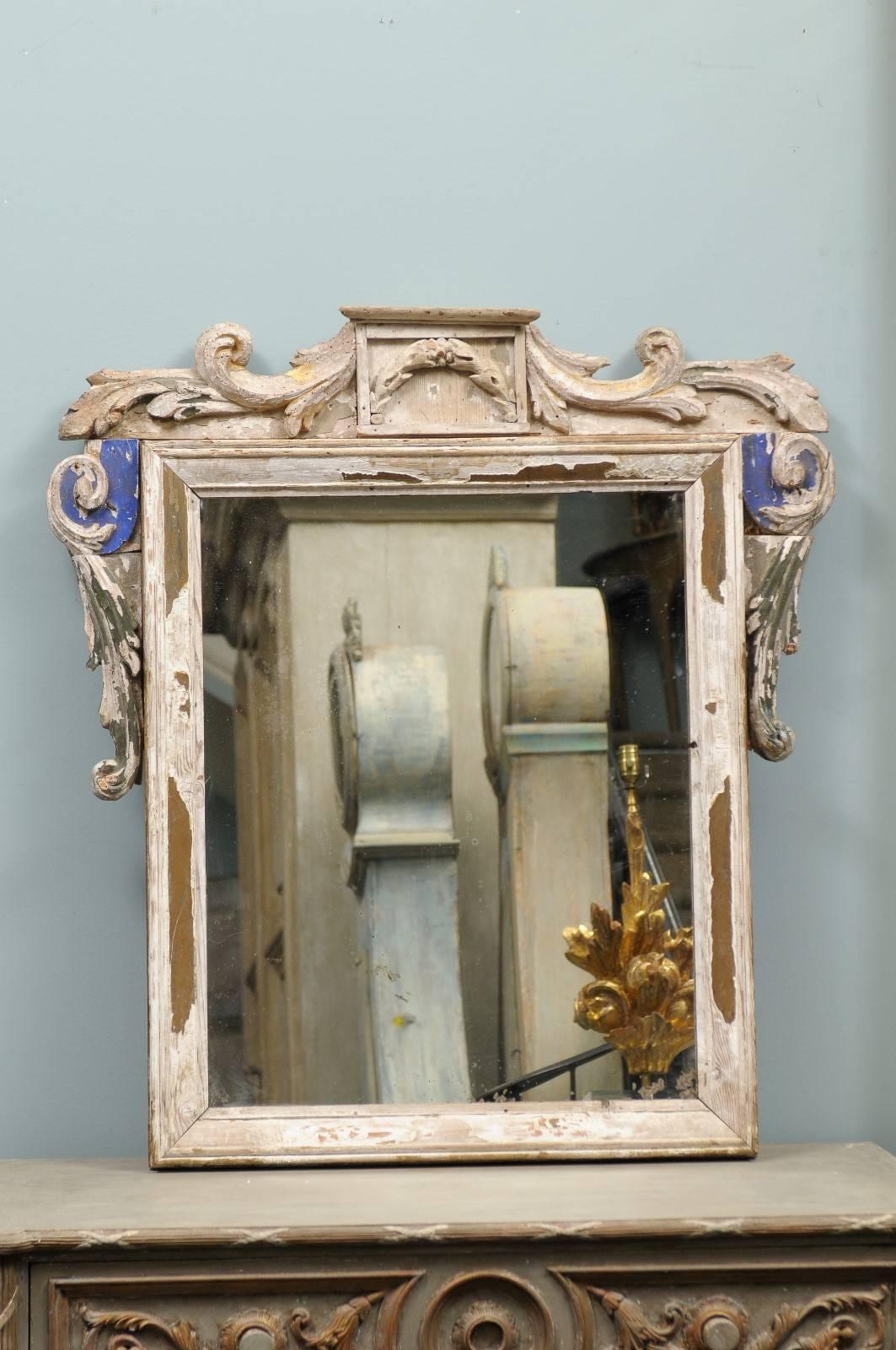 A carved Italian wood mirror made out of an old 19th century fragments. This Italian mirror features a nicely aged frame made of fragments. The crest is elegantly decorated with foliage motifs while the sides are ornate in their upper section with