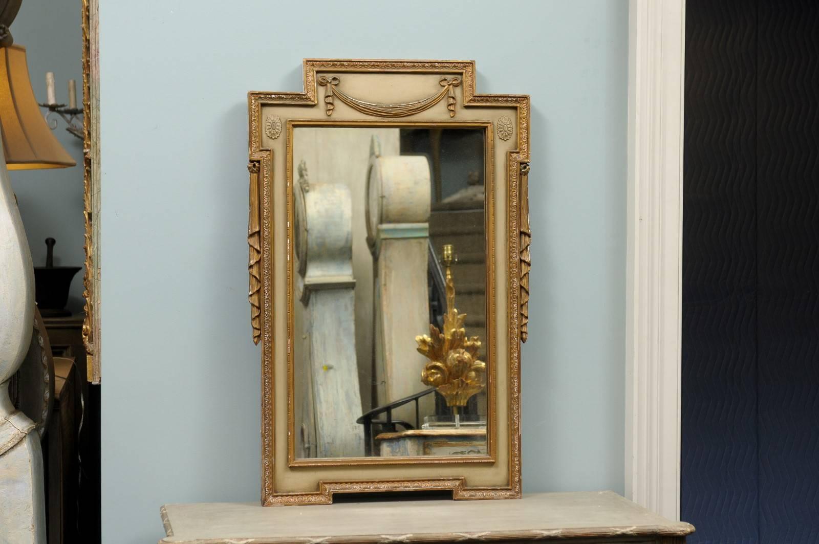 Une paire de miroirs suédois peints et dorés du début du 20e siècle. Cette paire de miroirs suédois présente un profil plutôt linéaire adouci par les motifs en tissu plié de chaque côté. Le cimier est décoré d'un délicat motif de houlette avec des