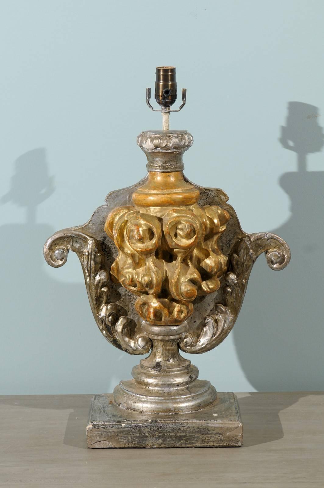 A single Italian table lamp from the 19th century. This Italian gilded table lamps is adorned with a fire pot gilded motif standing out from the silver gilded background with volutes and foliage motif on each side. The lamp is raised on a