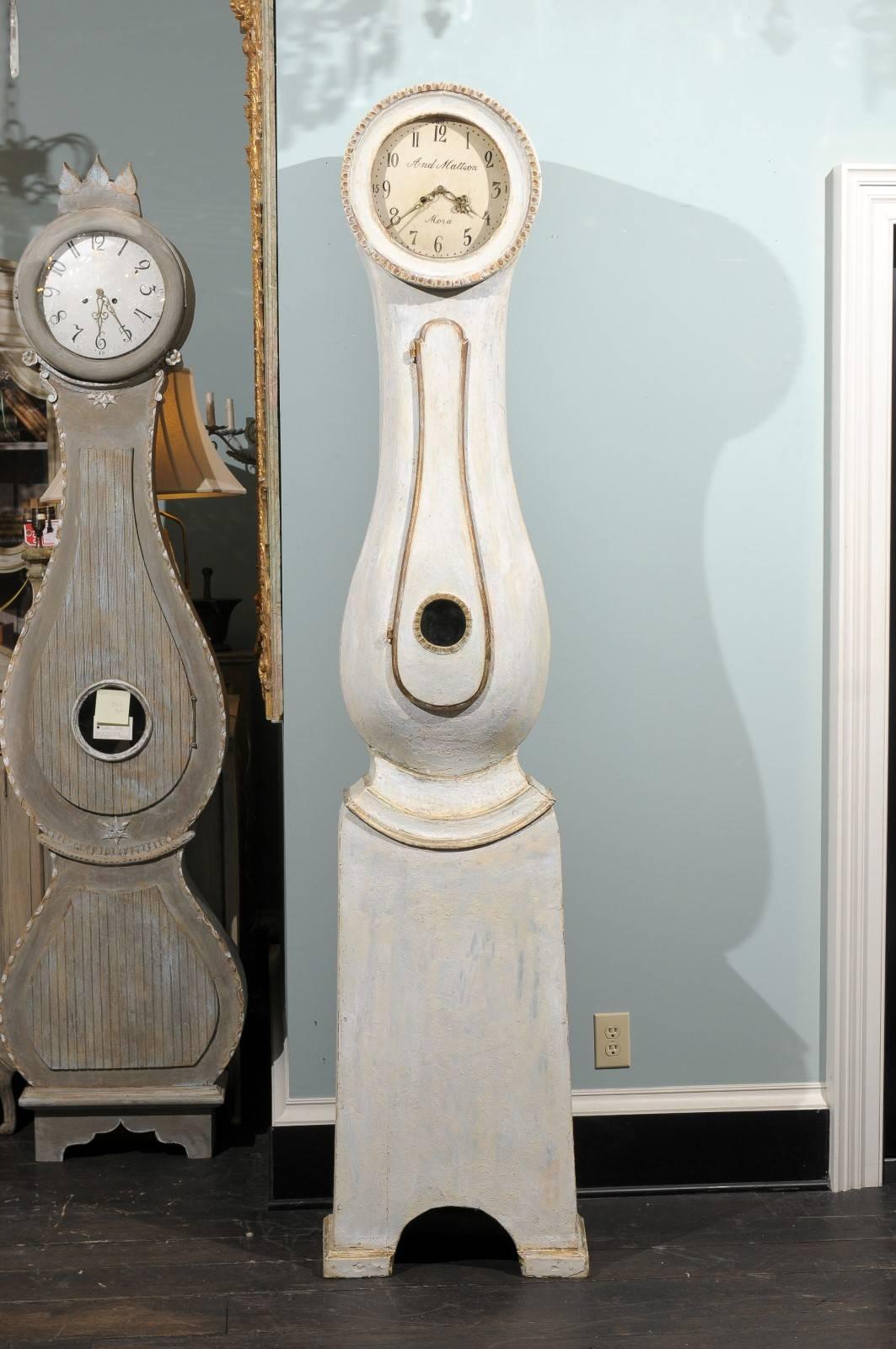 This exquisite Swedish 19th century white with a slight blue undertone and gilded accents clock is a lesson in subtlety. This clock retains it's original metal face, hands and movement.  From its elegant curves to the straightforward simplicity of