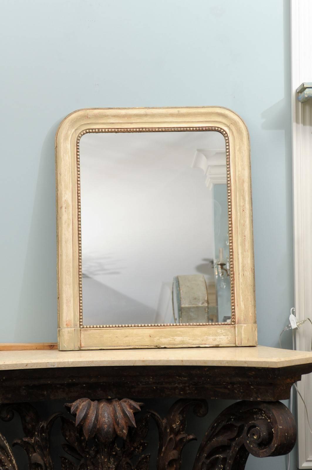A 19th century French Louis Philippe style cream colored mirror with hints of red-orange undertones. This French mirror has very subtle carved floral motifs throughout the surround. This mirror also has a nice bead-like motif around the edge of the