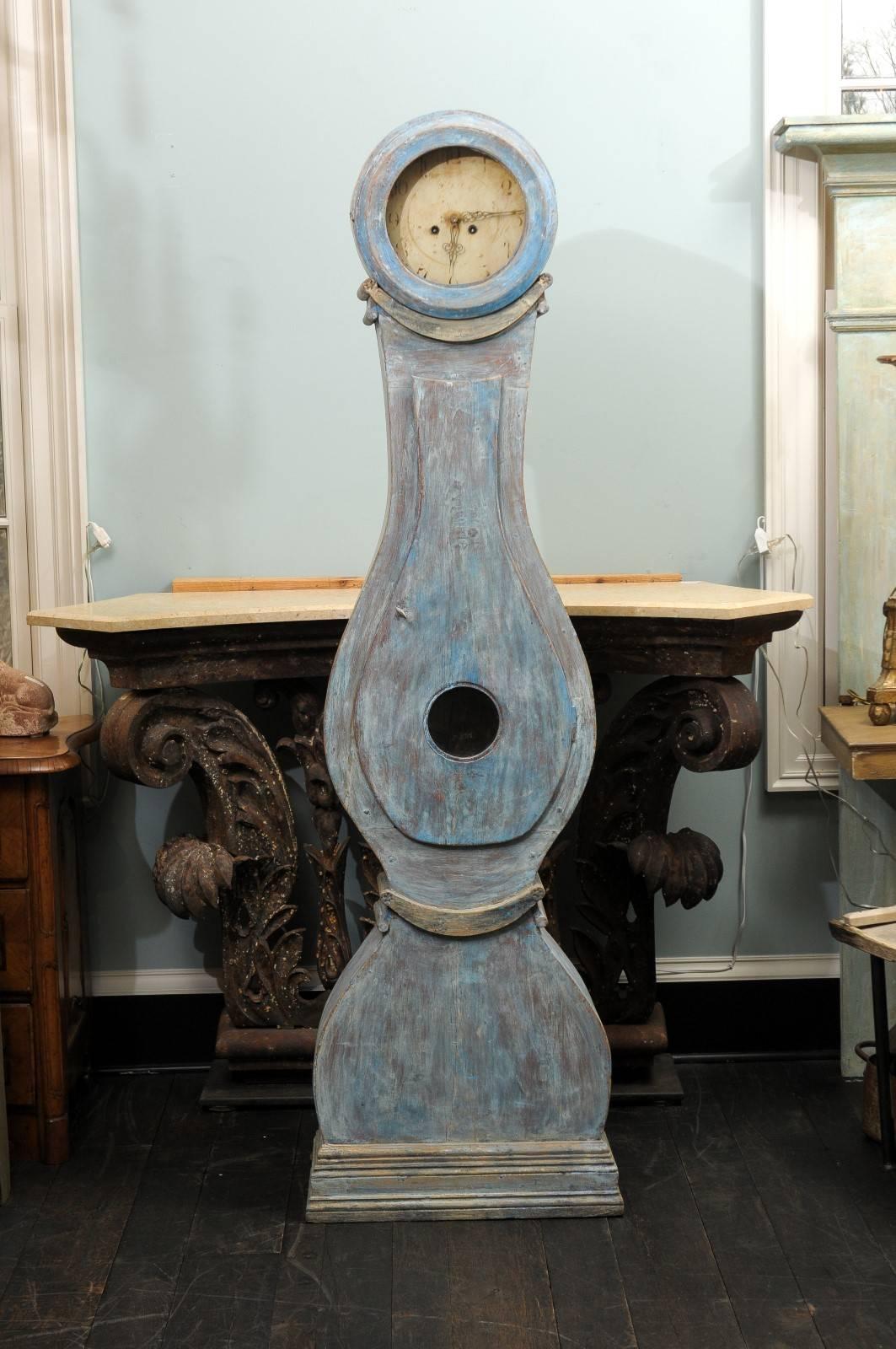 A 19th century painted blue, wooded Swedish clock. This Swedish clock is a very nice blue color with grey undertones. This clock retains it's original metal face, hands and movement.  This clock has a round face, leading down to a raindrop shaped