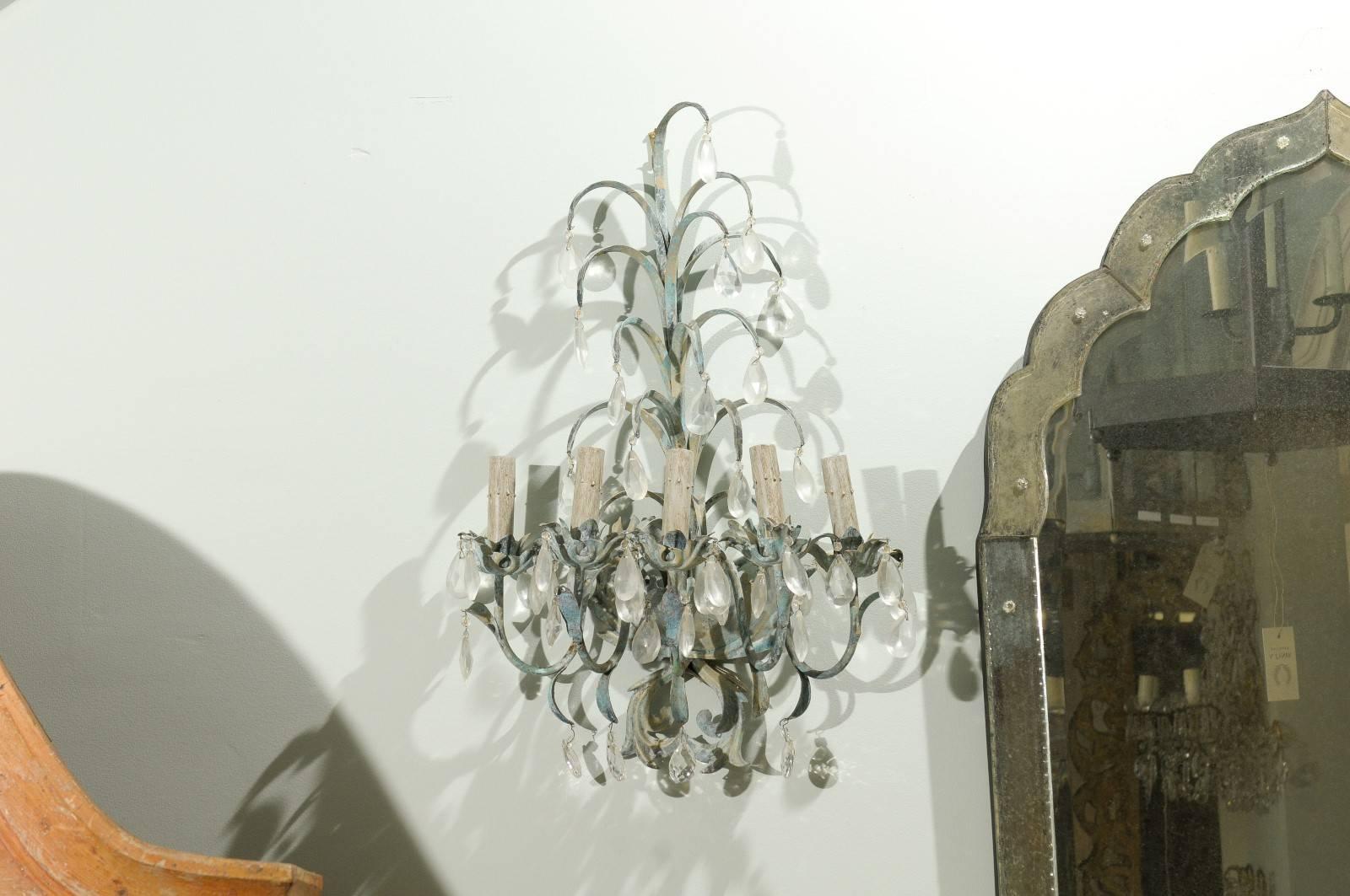 A pair of whimsical metal and crystal sconces. These French vintage sconces have five lights each. Each of these lights is supported by a sprouting foliage inspired bobèches. The upper part of these sconces has leaf-like over-hanging decorations