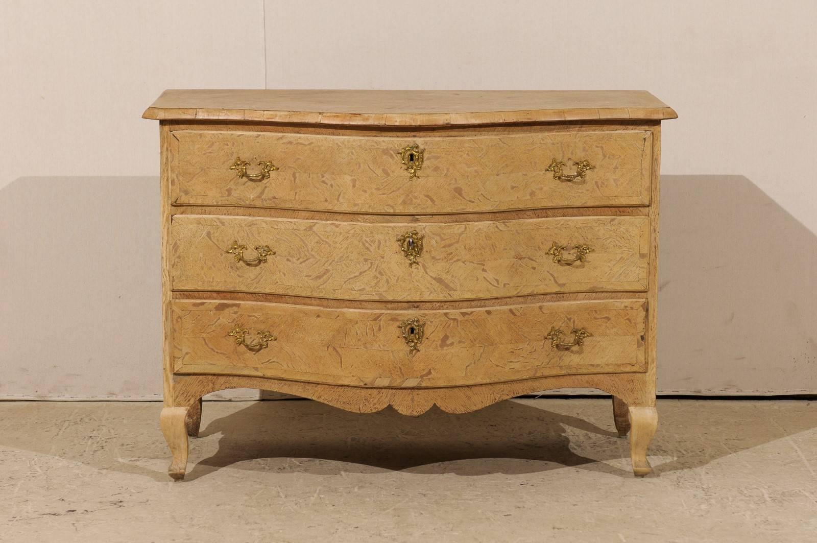 An 18th century Swedish Rococo serpentine commode. This Swedish period Rococo chest from the 18th century is made from oak and features a natural finish. Below the three convex drawers with Rococo style hardware is a scalloped skirt. The chest rests