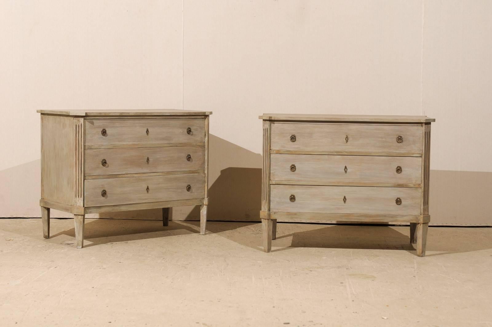 A pair of Swedish three-drawer chests. This pair of vintage Swedish painted wood chests from the mid-20th century features clean simple lines softened by the fluted and canted side posts and bevelled legs. The slightly overhanging top mimics in its