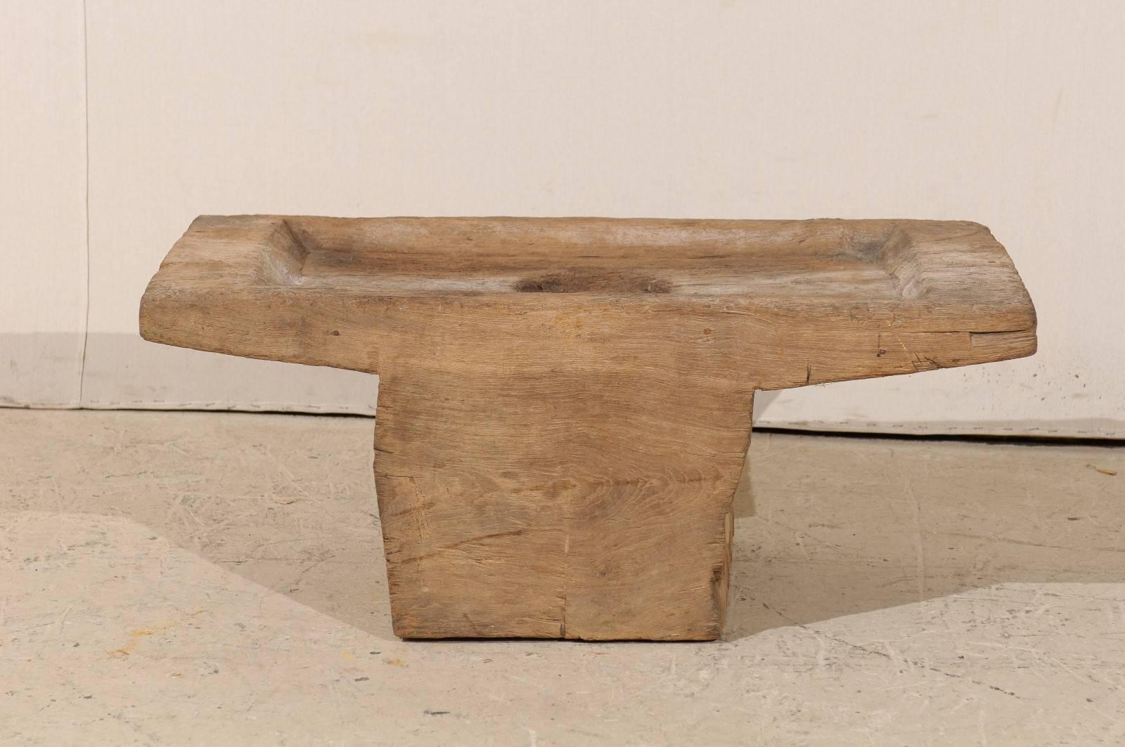 A unique and rustic wooden coffee table. Originally an Indonesian grain grinder from the early 20th century, this piece has been given a new life and makes for a great little coffee table. The color is of a light brown. This coffee table would look