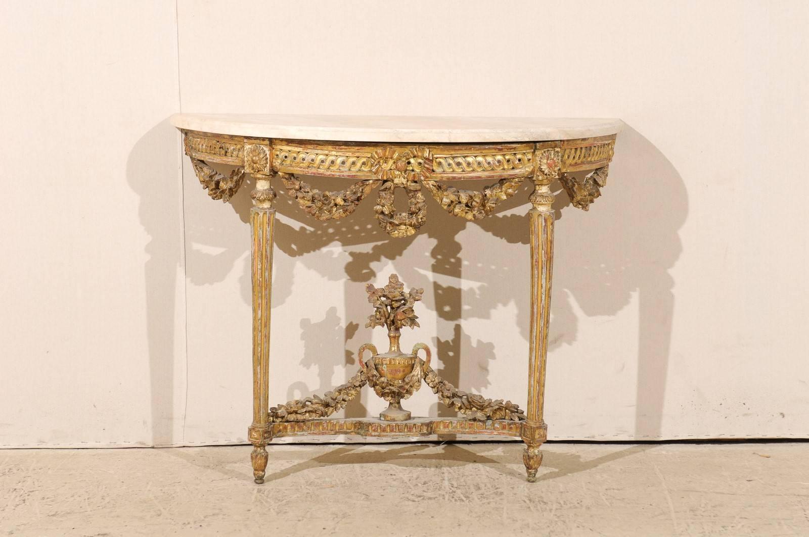 An Italian early 19th century marble-top console table. This beautiful giltwood console table with white marble top features a nicely carved apron with hanging floral swags and guilloche motif. The two legs, topped with floral accents, are tapered