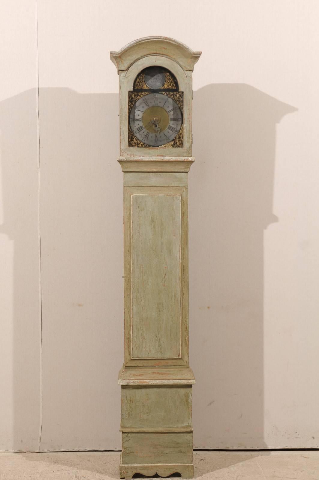 A Swedish 19th century long case clock. This Swedish clock features a linear body with an arched crown and exquisitely decorated face including pewter ring and both roman and traditional numerals, as well as intricate gilded ornaments in the