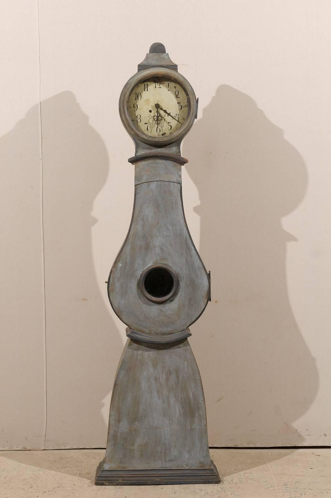 A 19th century Swedish clock. This Swedish clock has a nicely adorned crest and fluid curves throughout the head and body. This clock retains it's original metal face, hands and movement.  The tear drop single-hinged door opens from left to right