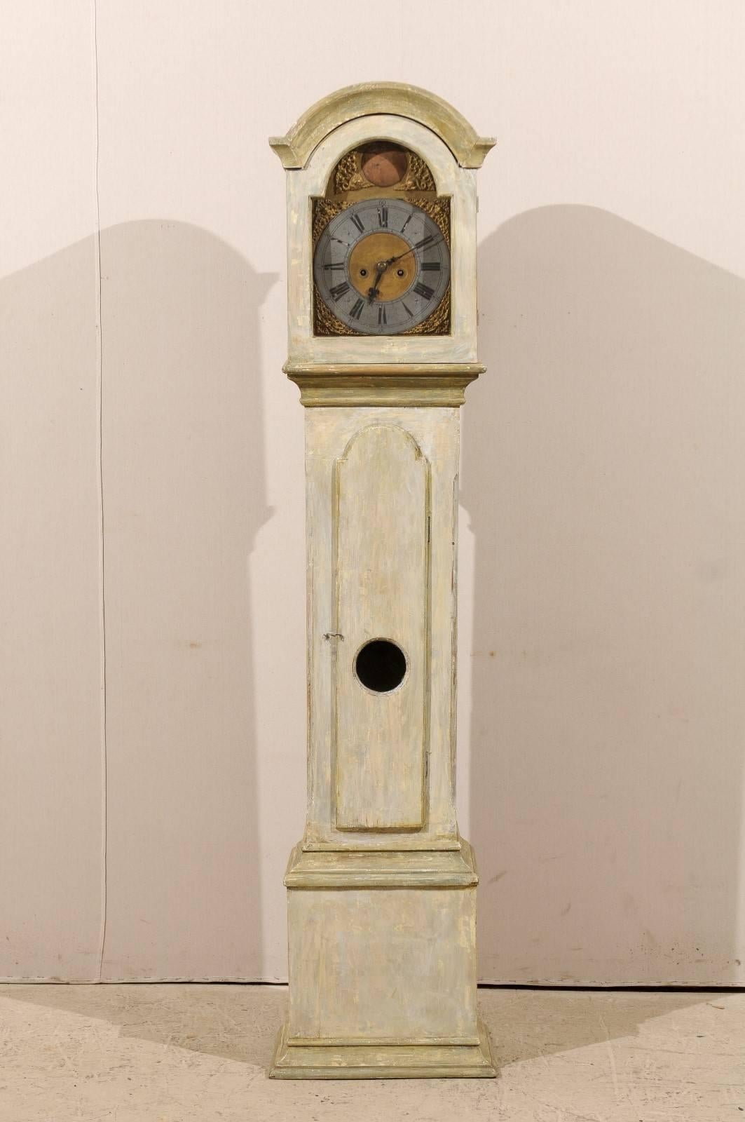 A Swedish 19th century long case clock. This Swedish straight body clock features a bonnet crest and a pewter ring face over a gilded background.  This clock retains it's original metal face, hands and movement. Intricate ornaments adorn the corners
