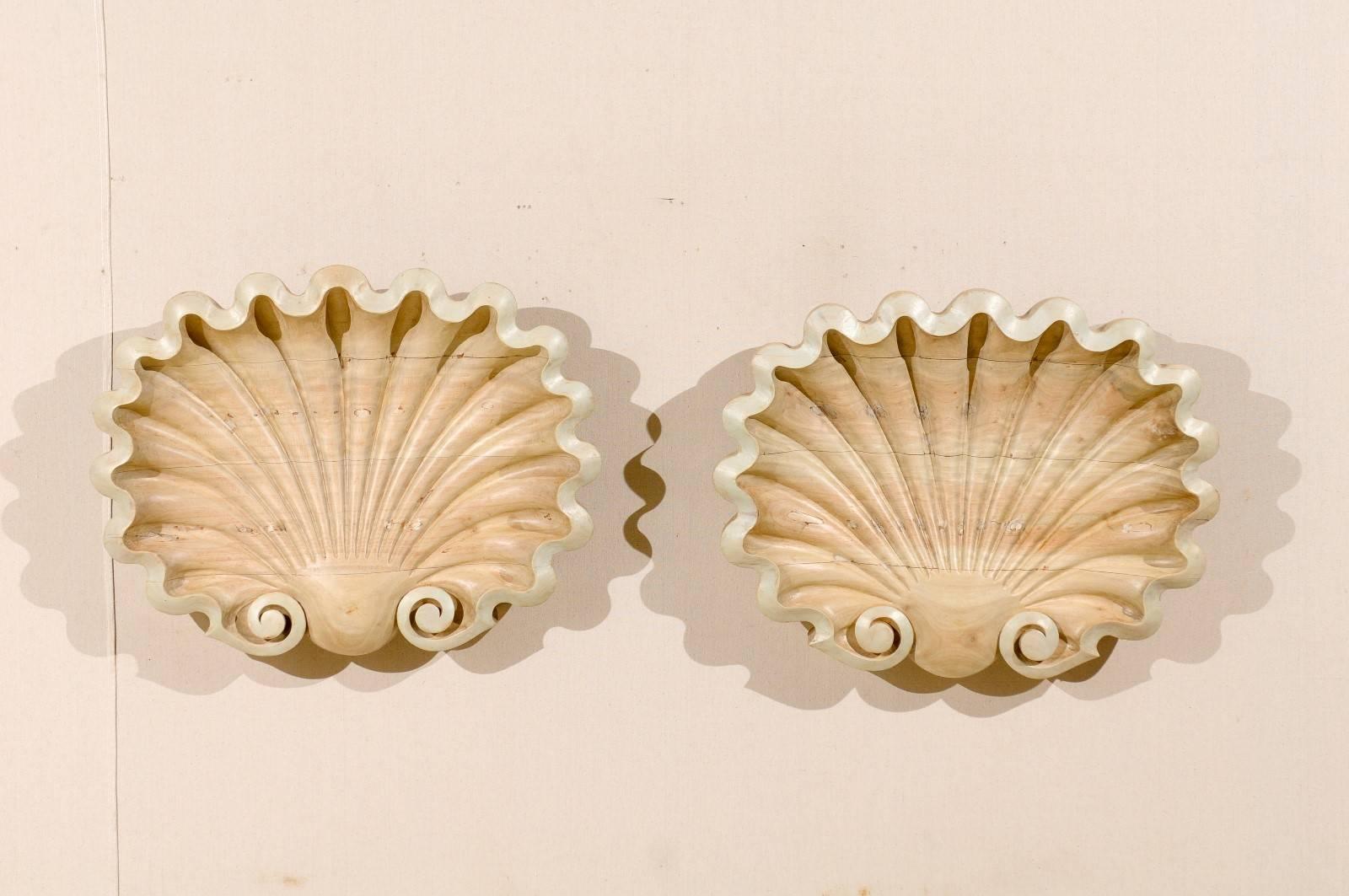A carved, bleached and painted wood three dimensional shell plaque. These shell wall plaques would add a touch of antique classicism / Renaissance look to any room. The wood has been bleached to create the pretty soft tan color. These shells also