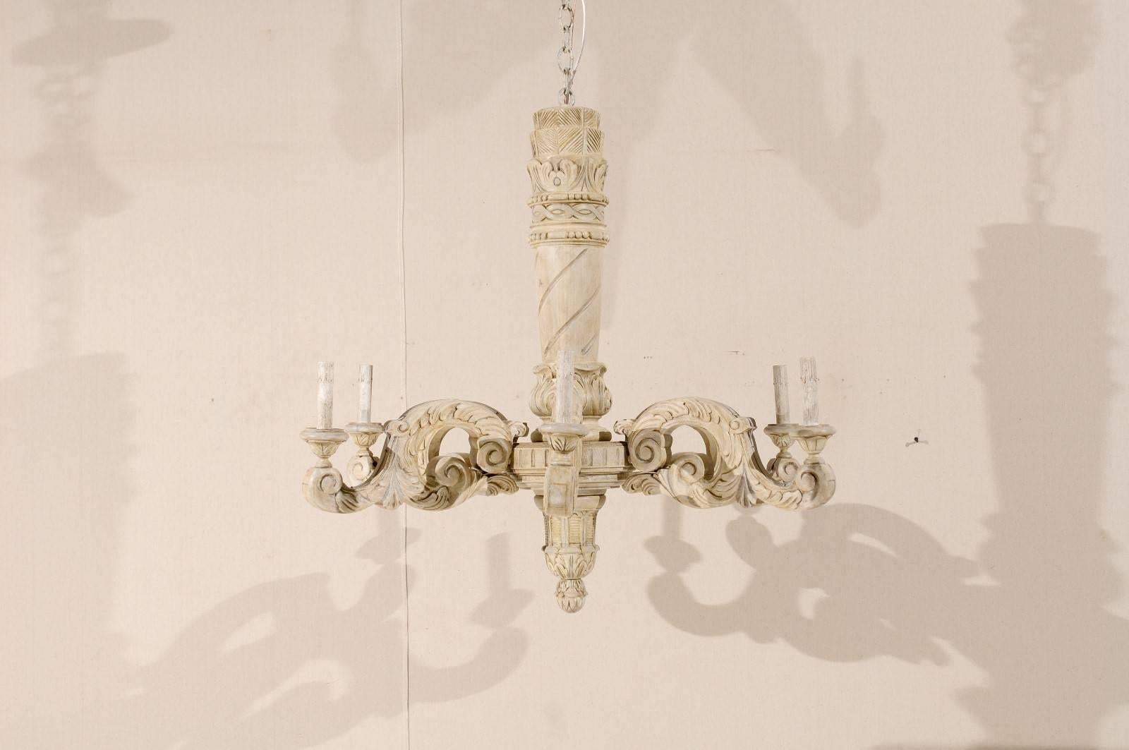 A French carved and painted wood six-light chandelier. This lovely French chandelier from the mid-20th century features a carved central column with six scrolled arms emerging outward that are each adorned with acanthus leaf motifs. The carved