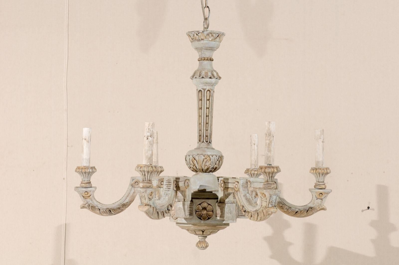 A French vintage six-light painted and carved wood chandelier. This French chandelier from the mid-20th century features a central column with carved foliage decor. The chandelier has six arms with interesting shapes which go up and out at rigid 90