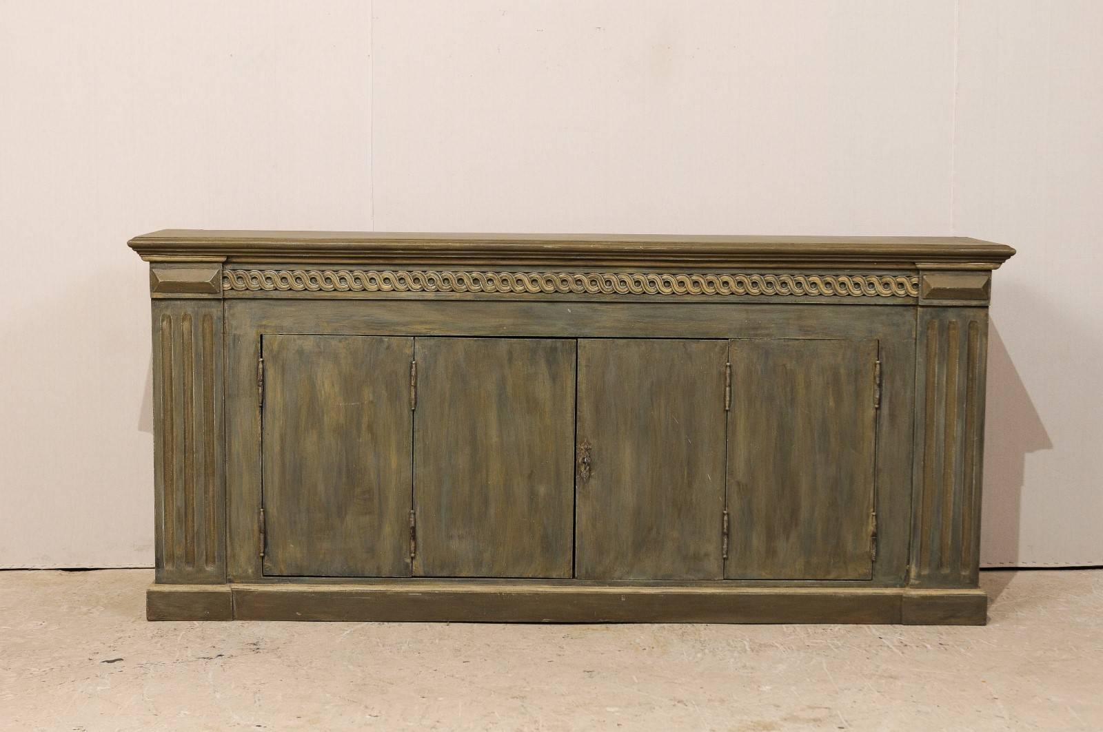 A Brazilian painted wood enfilade or buffet cabinet. This long buffet features two bi-folding doors that open wide for great storage options. The sides of this cabinet are flanked with flat fluted pilasters and the top rail has nice Guilloche carved