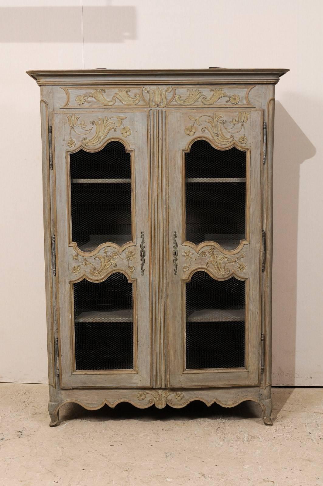 A French painted wood two-door cabinet. This French cabinet from the early 20th century features an elegantly carved floral motif about the top and bottom rails, as well as the upper and mid-section of the doors. The cabinet sides are double
