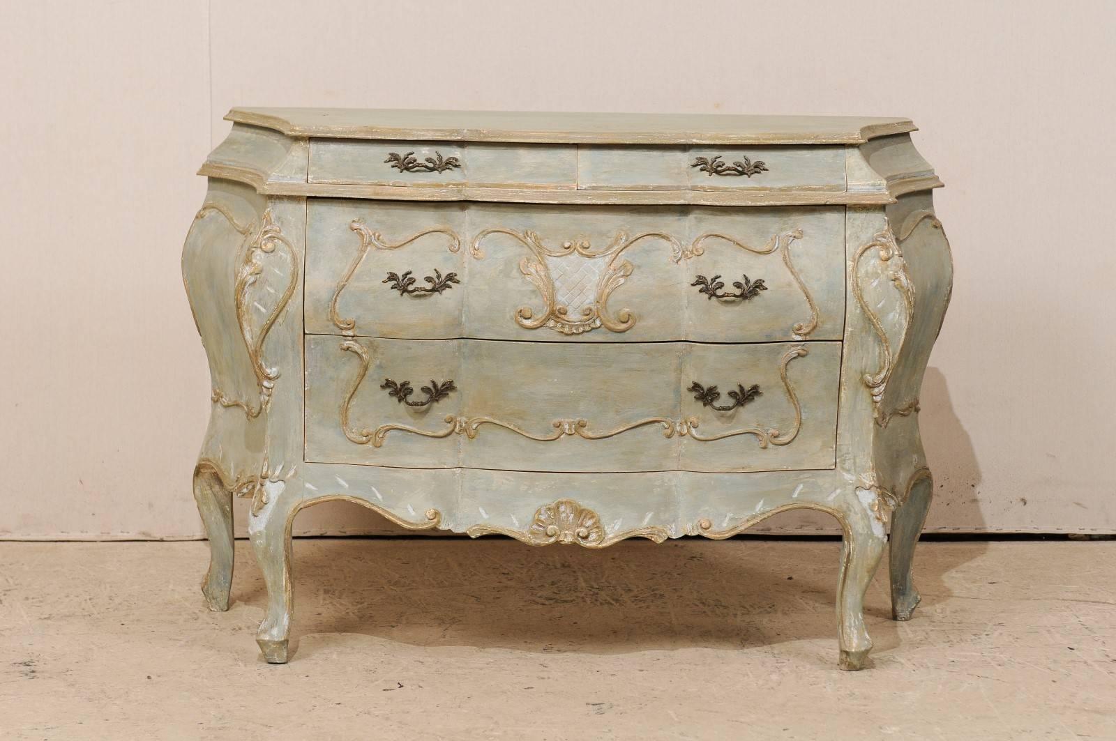 An American vintage four-drawer painted wood Bombé chest. This American Bombé chest from the late 20th century is ornately decorated with a shell carving on the skirt and cartouche outline around the drawers and chest sides. This Bombay style chest