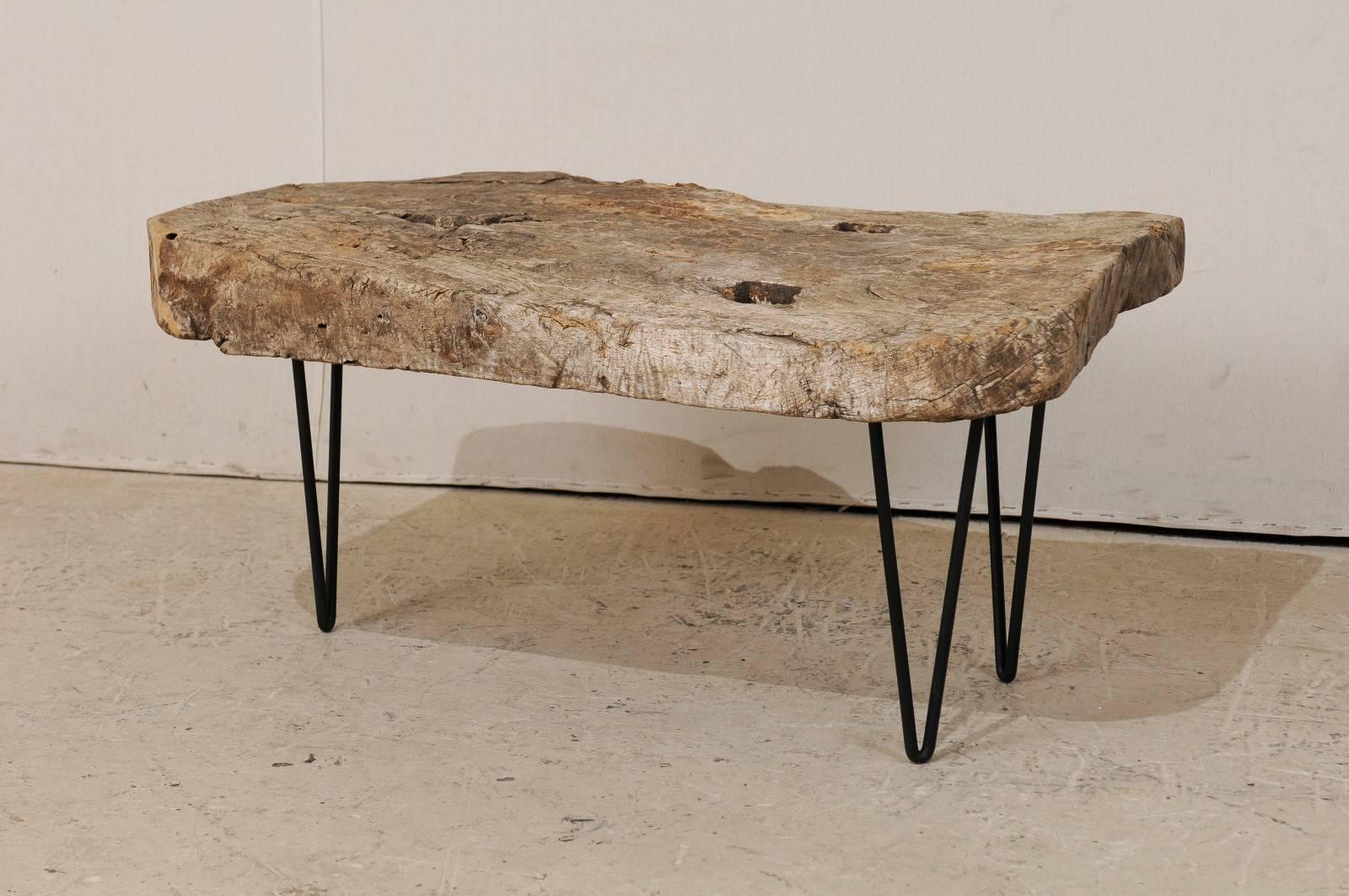 A custom coffee table of old Spanish wood. This rustic yet chic coffee table is made up from the top of a 19th century Spanish work table. The holes within the tabletop are where the feet were originally attached, and gives the top great character.
