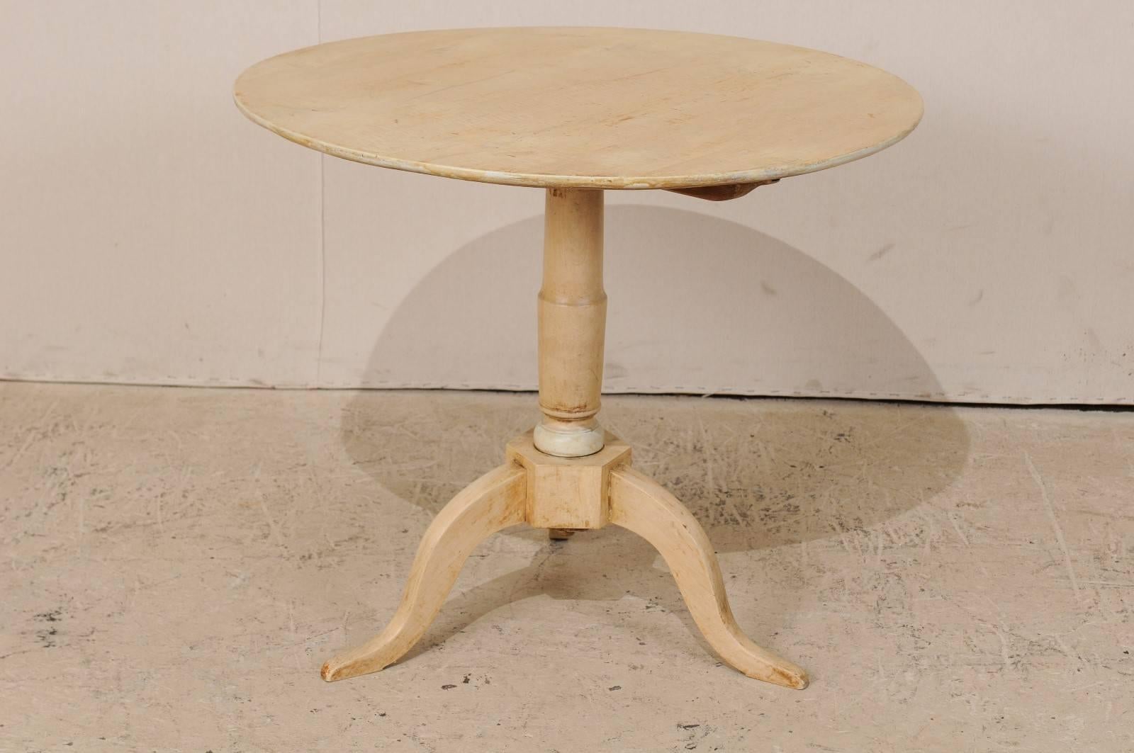 A Swedish 19th century round occasional table. This Swedish table, circa 1860, features a round top with a central pedestal column and tripod feet. The table is made of a bleached birch wood and there is a hint of accent paint around the base of the