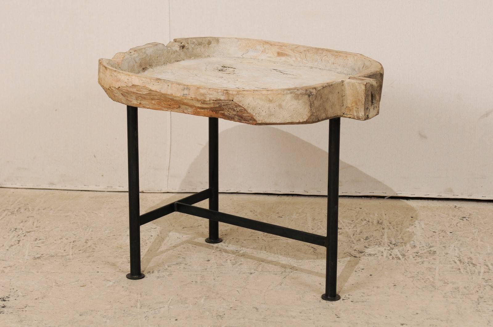 A Spanish wood trough coffee table. This unique coffee table features a top made from a Spanish, 19th century wood trough which was likely used during the process of cheese making. The natural wood top of this table is supported by a custom metal