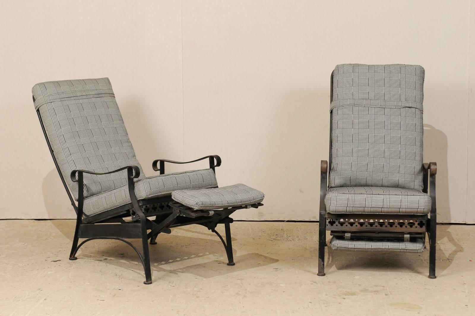 A pair of American Mid-Century reclining patio chairs. This pair of vintage iron patio chairs from the mid-20th century feature simple lines with a sweet clover and dot cut-out motif about the front seat rail. These patio chairs recline back,