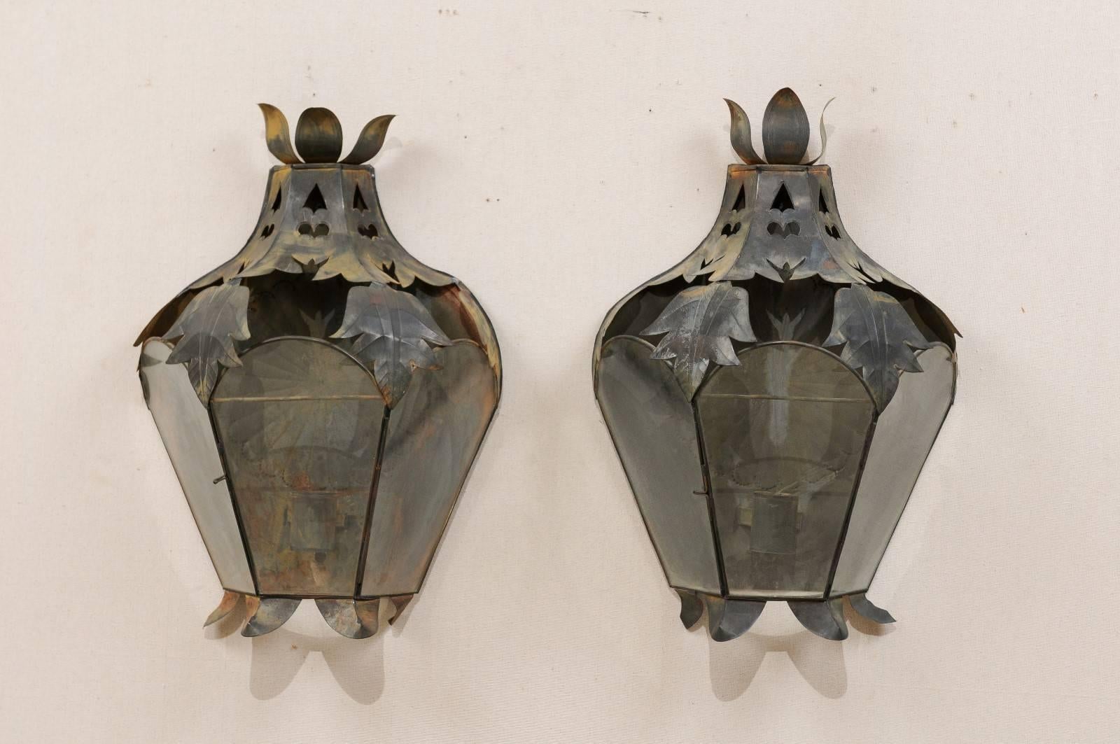 A pair of Mexican Folk Art sconces. This pair of Mexican single-candle sconces have been handcrafted from old tin, which has a nice, warm patina. This pair of Folk Art sconces are lantern style and would look charming set with a single candle in