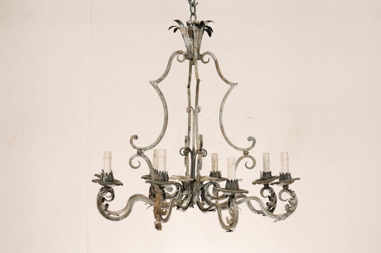 A French eight-light painted iron chandelier. This vintage French chandelier is adorned with ornate acanthus leaves on the scrolled arms. The top crown consists of a series of slender, down-turned leaves. This Mid-Century chandelier would work