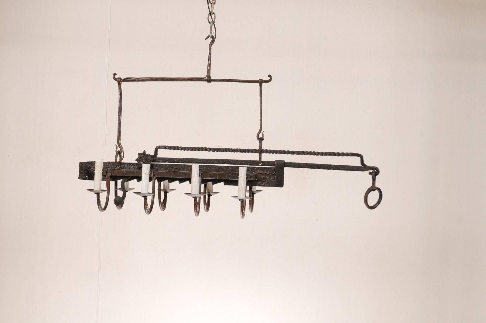 A French Mid-Century, eight-light forged-iron chandelier made from a 19th century spit-jack. A spit-jack is a type of rotisserie that was once common in fireplaces. This chandelier has eight swooping arms which connect to the central spit-jack. This