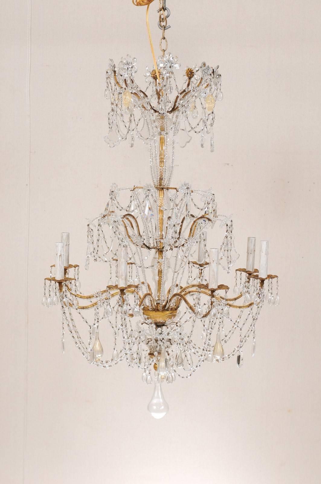 An Italian eight-light crystal and handblown glass chandelier. This mid-century Italian gilded iron chandelier is adorn with a collection of various crystals, swagged Italian glass trim and handblown glass throughout with a large, tear dropped