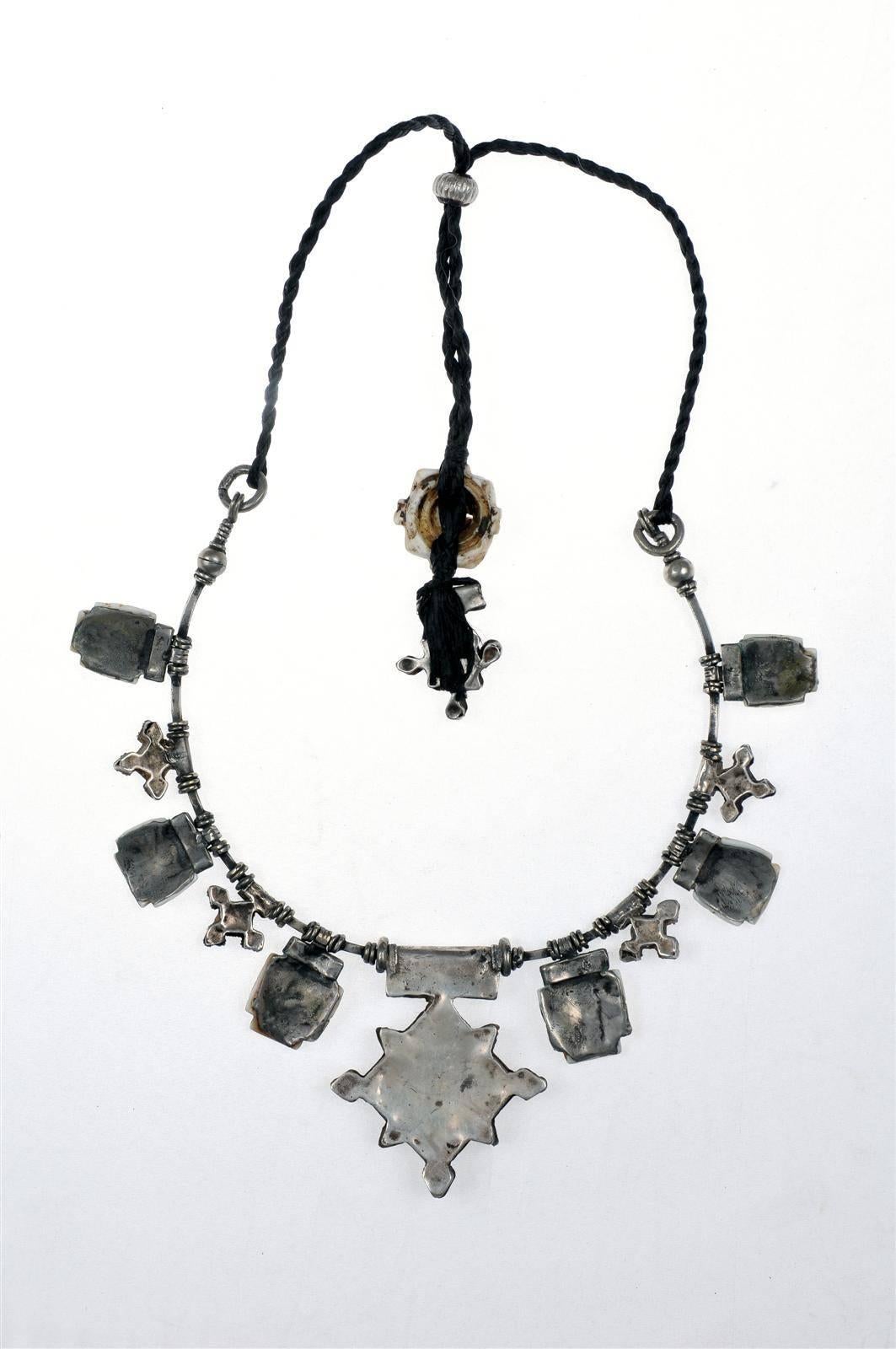 A custom-made necklace by Famous Moroccan jeweller Chez Faouzi of Marrakech. Necklace is made of antique moroccan silver and conus shell charms with the signature Faouzi Back neck charm. Black chord is adjustable to 35.