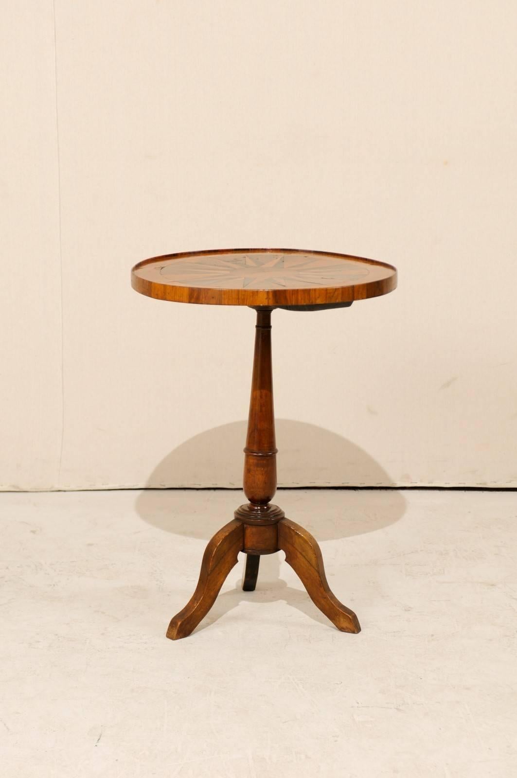 An Italian 19th century round pedestal table. This Italian pedestal table of stained fruitwood features a lovely compass star-shaped inlaid top of walnut and satin wood. The table rests on a central pedestal column and tripod feet. This 19th century